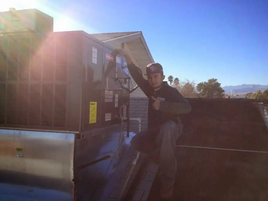HVAC technician performing Air Duct Repair on a rooftop unit in Greensboro